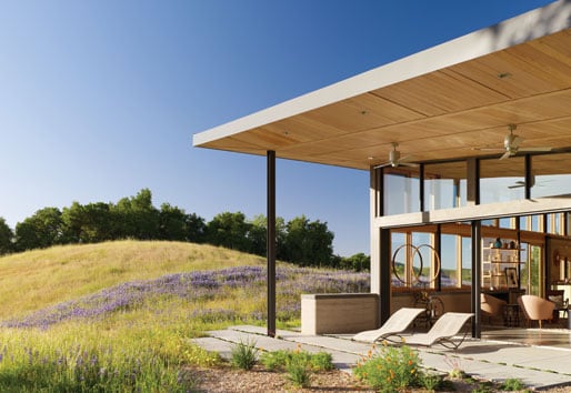 A hilltop ranch home with a large overhang covering a patio that’s connected to the home through large Liftslide Doors.
